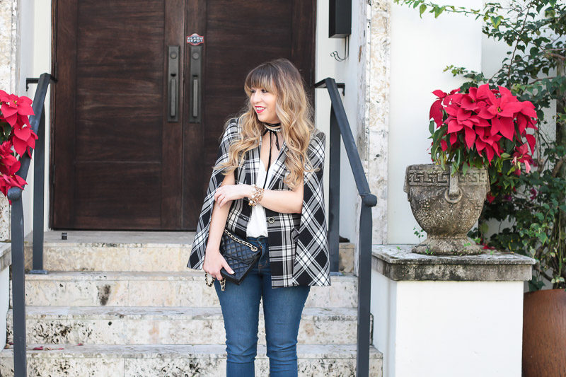 Miami fashion blogger Stephanie Pernas styles a plaid cape blazer with a pearl choker and jeans for a casual polished look 