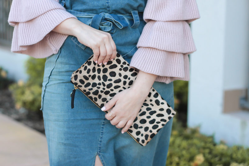 Miami fashion blogger Stephanie Pernas styles a Clare V leopard foldover clutch with a denim dress and ruffle sleeve sweater