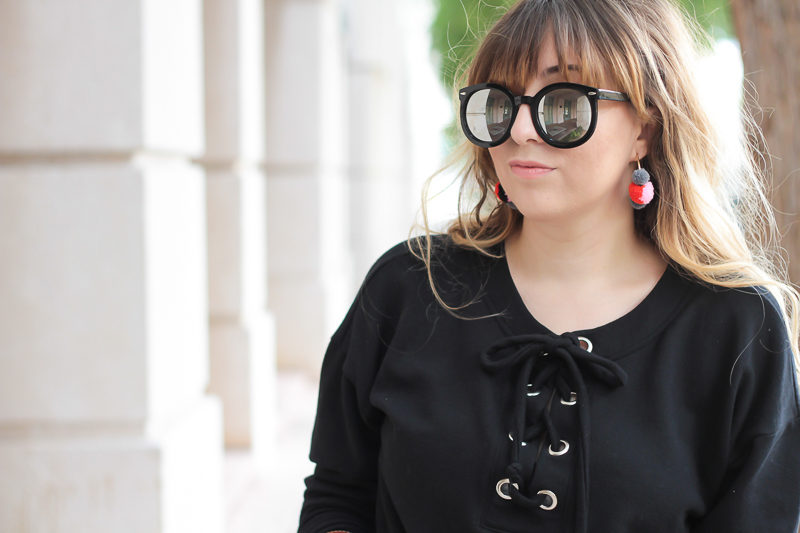 Miami fashion blogger Stephanie Pernas wearing a black lace up sweater and Baublebar pompom hoop earrings