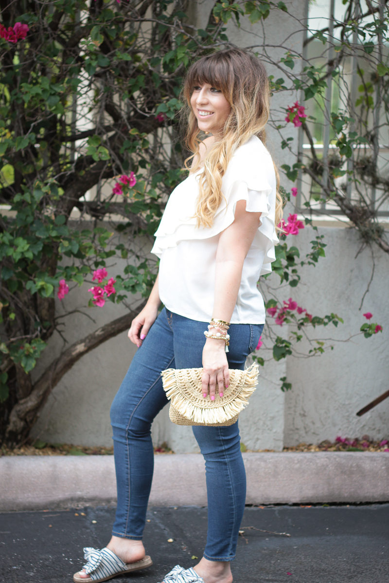 Miami fashion blogger Stephanie Pernas styles a one shoulder top with jeans and bow slides for a cute spring outfit idea 