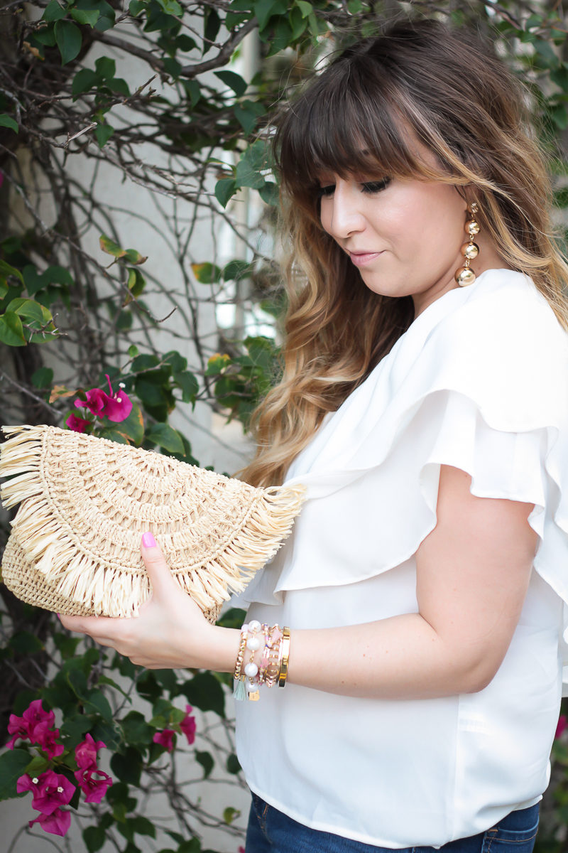 Miami fashion blogger Stephanie Pernas styles a straw clutch with a cute one shoulder ruffle top and gold ball drop earrings