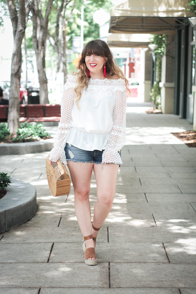 Miami fashion blogger Stephanie Pernas styles a white lace off the shoulder top and jean shorts for summer 